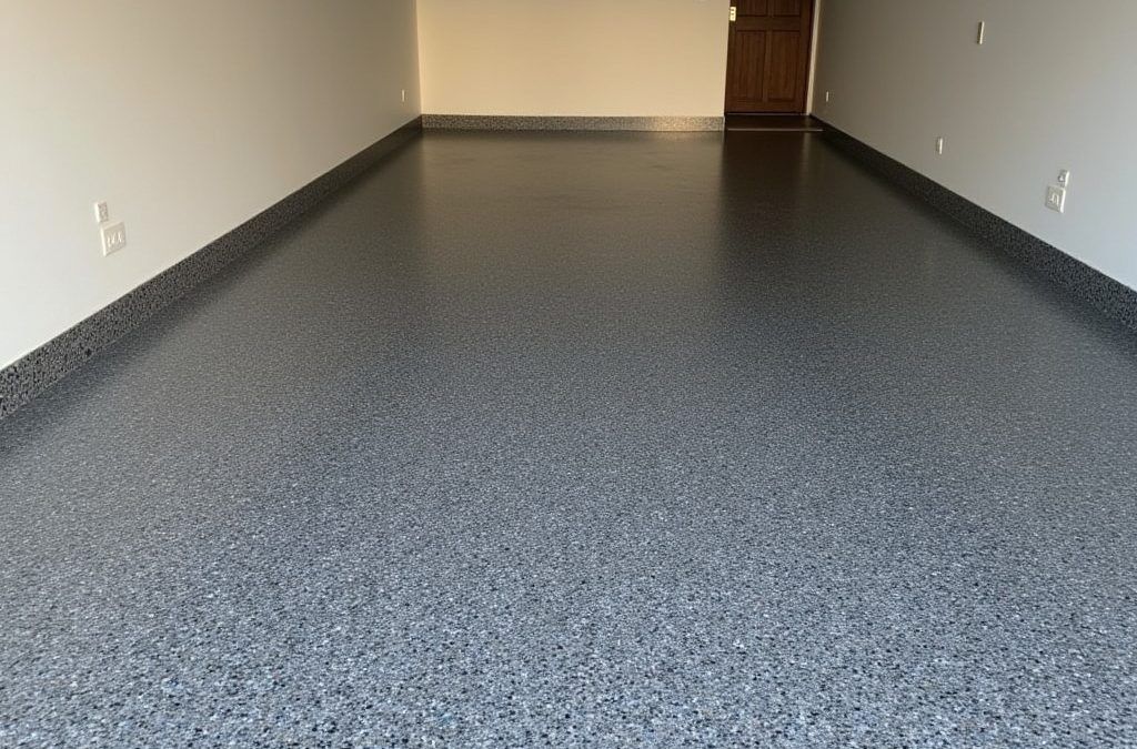 Garage floor coated in speckled gray epoxy. Walls are beige. Brown door in the back.