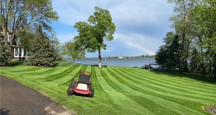 Imag of a perfeclty cut lawn. You Can see a large lawn in Wayzata with a lake view. The Ground is hilly and the lawn is perfectly cut in straight lines. 