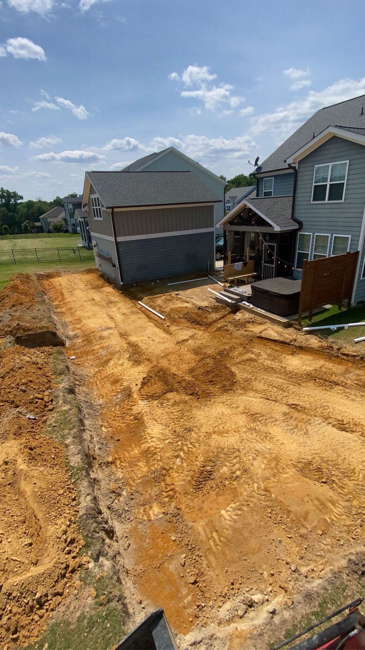 A dirt road leading to a house under construction.