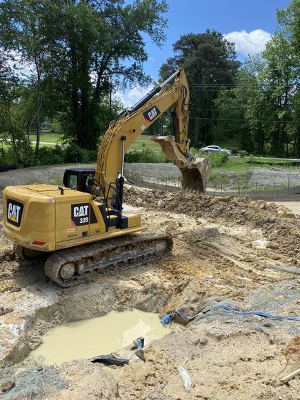 A yellow excavator is digging a hole in the dirt.