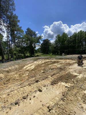 A large dirt field with trees in the background on a sunny day.