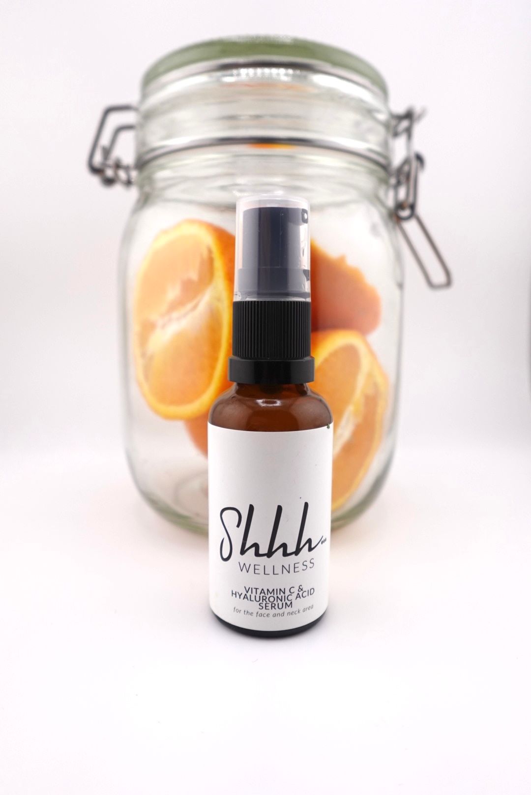 A jar of sliced oranges with a brown bottle of beauty serum in front