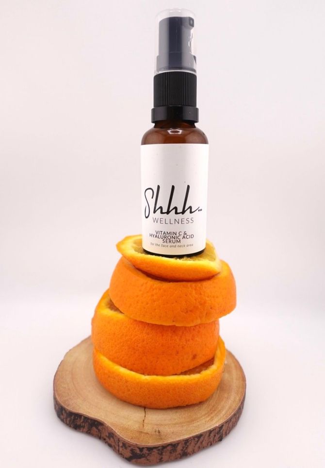 Brown bottle with black pump, atop orange peel stack, on wood slice, with white label reading