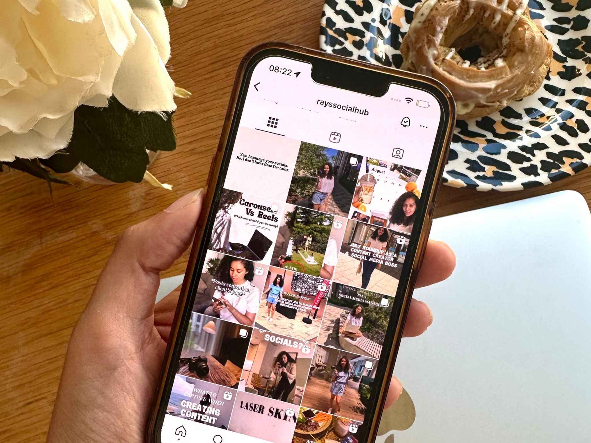 Person using a smartphone, tapping the screen. Coffee cup, notebook, and pen on a white table.