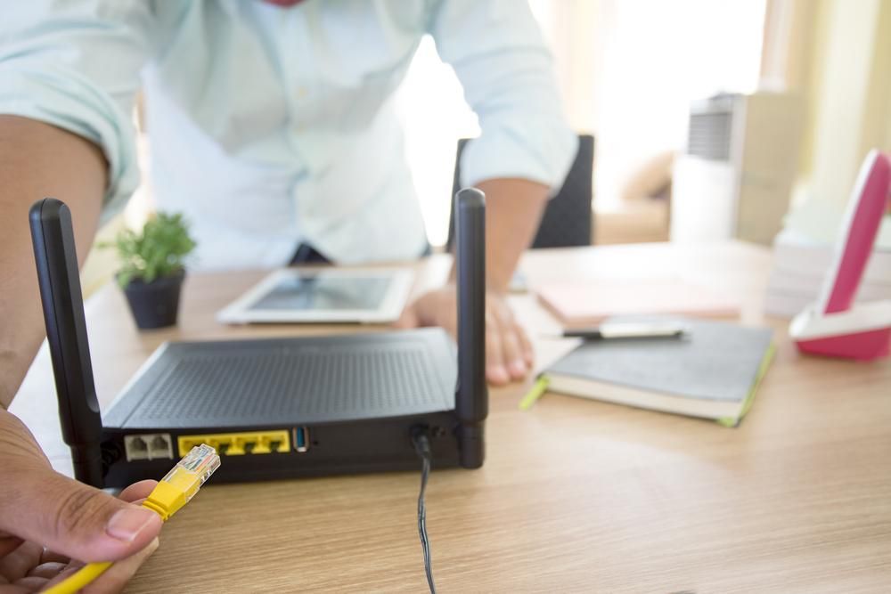 A Man is Plugging a Yellow Cable Into a Router — River City Communications In Melinga, NSW