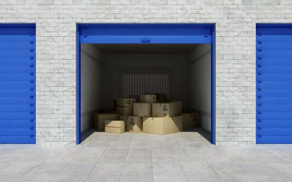 A stack of cardboard boxes in a garage with blue doors.