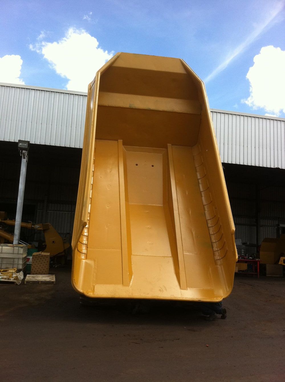A Large Yellow Dumpster is Parked in Front of a Building — Wright's Welding Operations In Ryan, QLD
