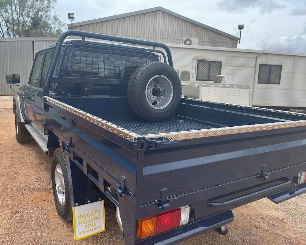 A Blue Truck With a Spare Tire in the Bed is Parked in Front of a Building  — Wright's Welding Operations In Ryan, QLD