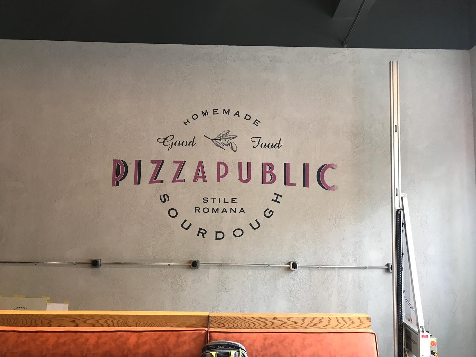 Muur van restaurant Pizza Public met paarse letters: 