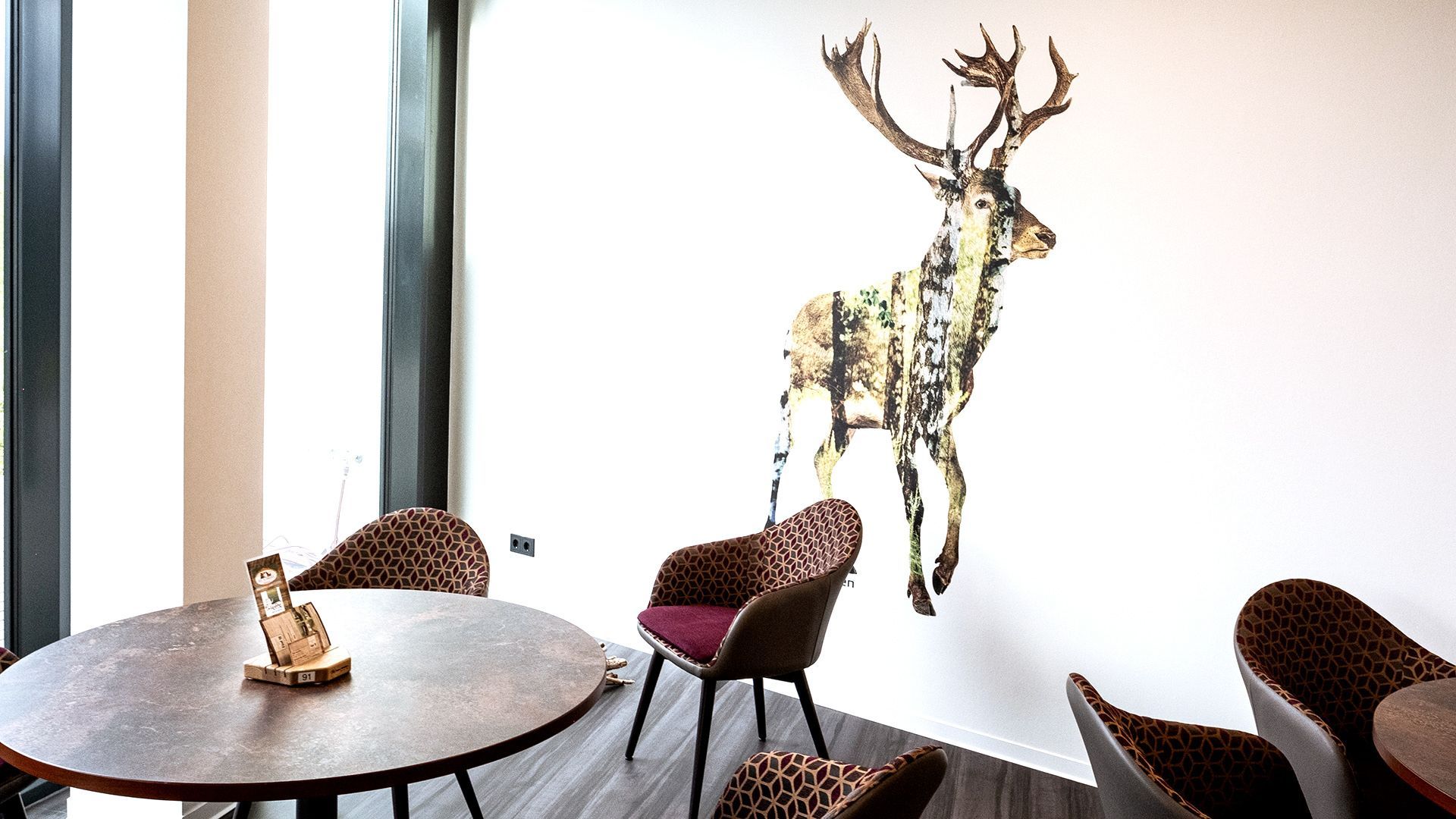 Eethoek met een hertenkunstwerk aan de muur, ronde tafel en stoelen met patroon.