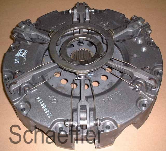 Gruppo spingidisco della frizione per auto, in metallo grigio scuro con scanalature centrali, su sfondo beige.