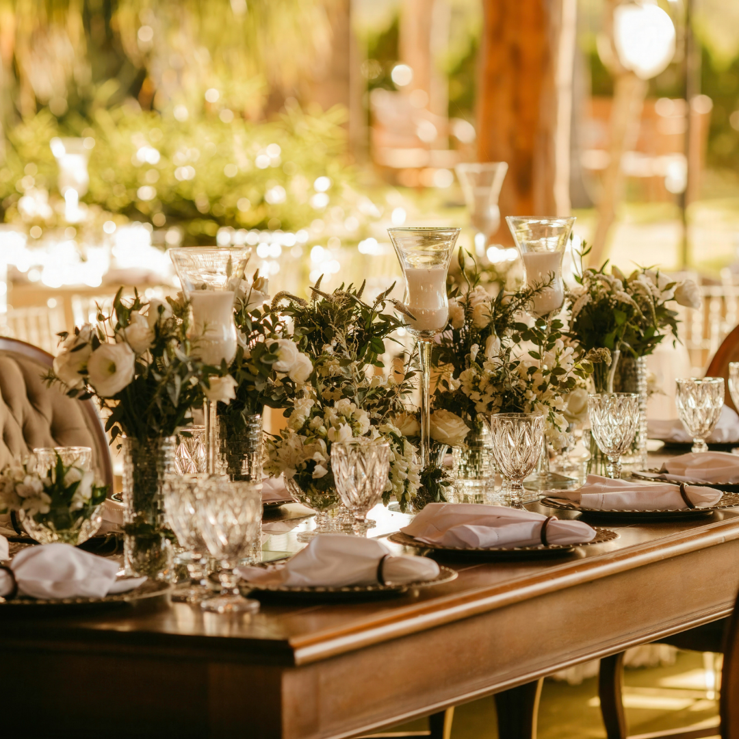 Elegant wedding reception table with white flowers, candles, and place settings.