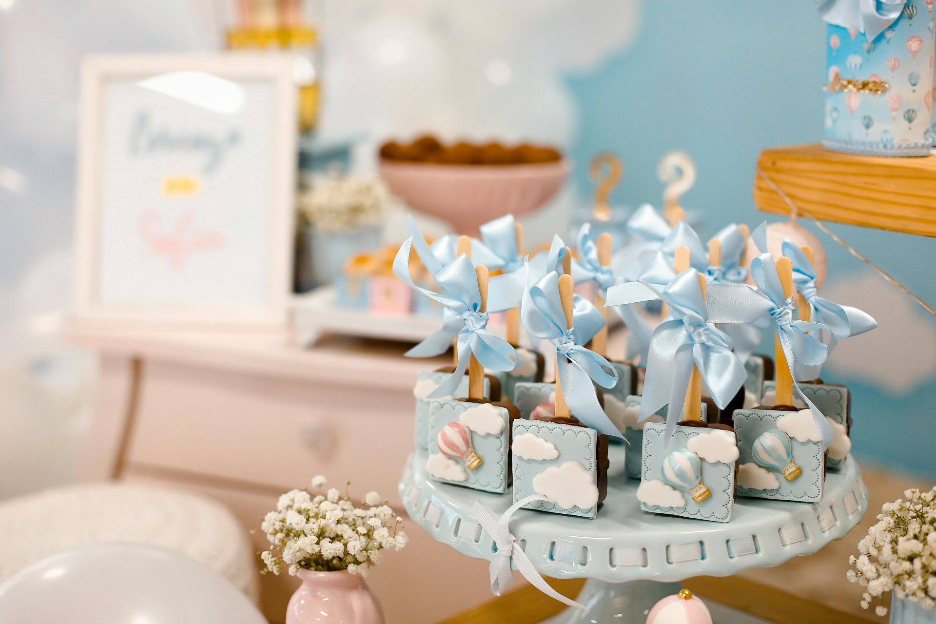 Party treats on a blue cake stand with sky-themed decorations: blue bows, clouds, and hot air balloons.