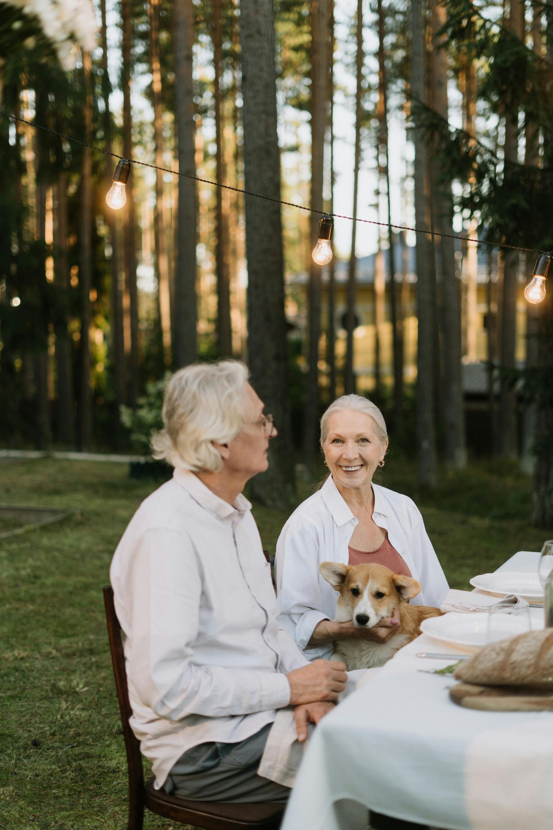 Senior couple with dog at outdoor table set for dinner.