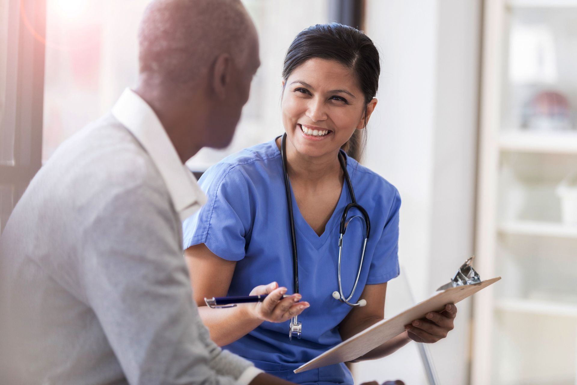 A nurse is talking to a patient while holding a clipboard.