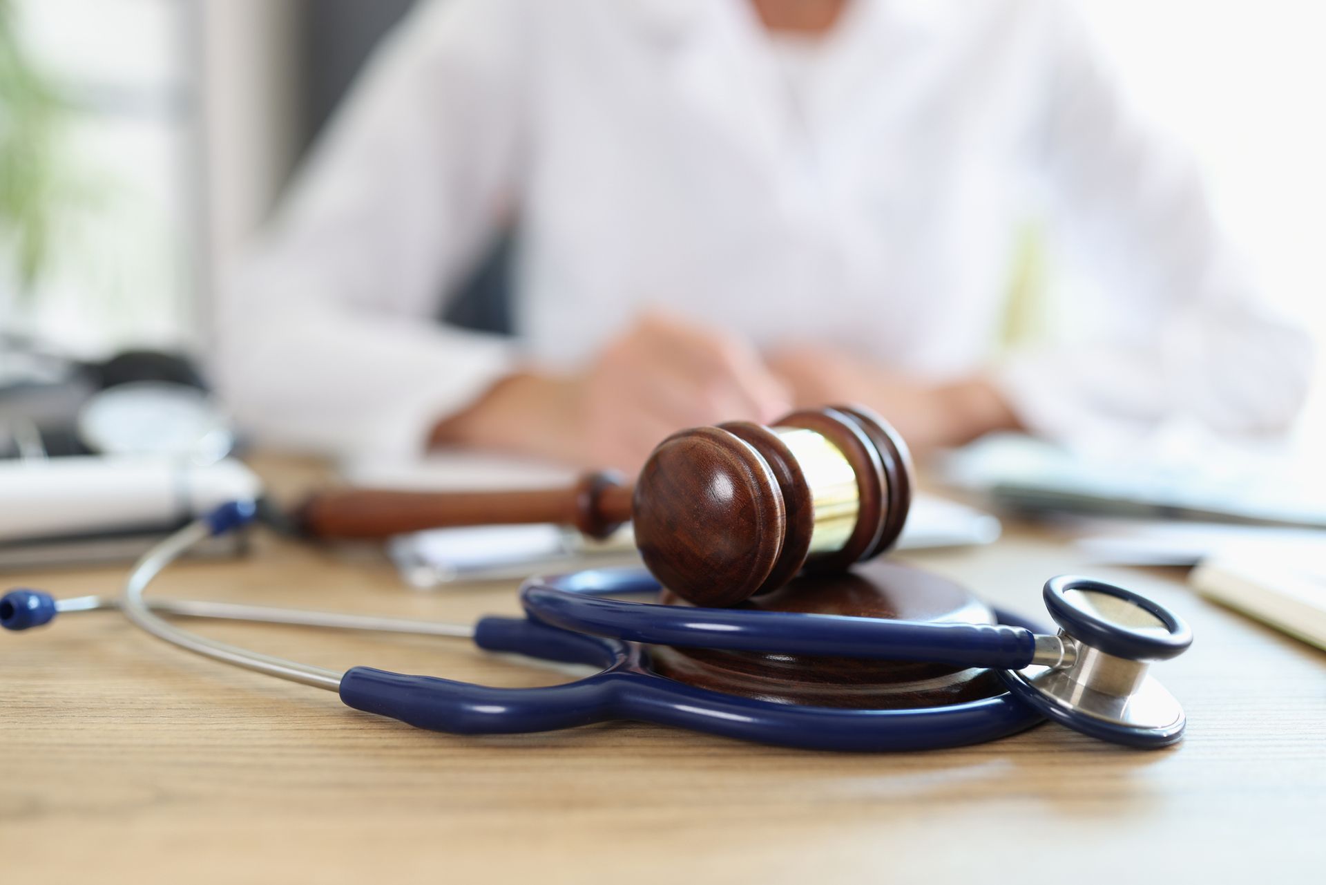 A judge 's gavel is sitting on top of a stethoscope on a table.