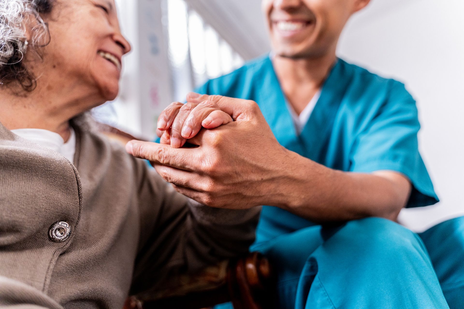 A nurse is holding the hand of an elderly woman.