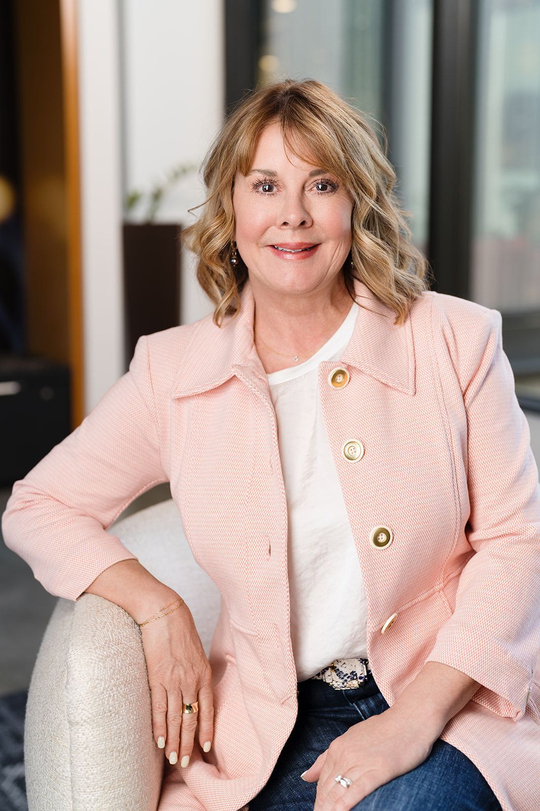 A woman in a pink jacket is sitting on a chair. Gayle Morris  Real Estate | GUIDE Real Estate