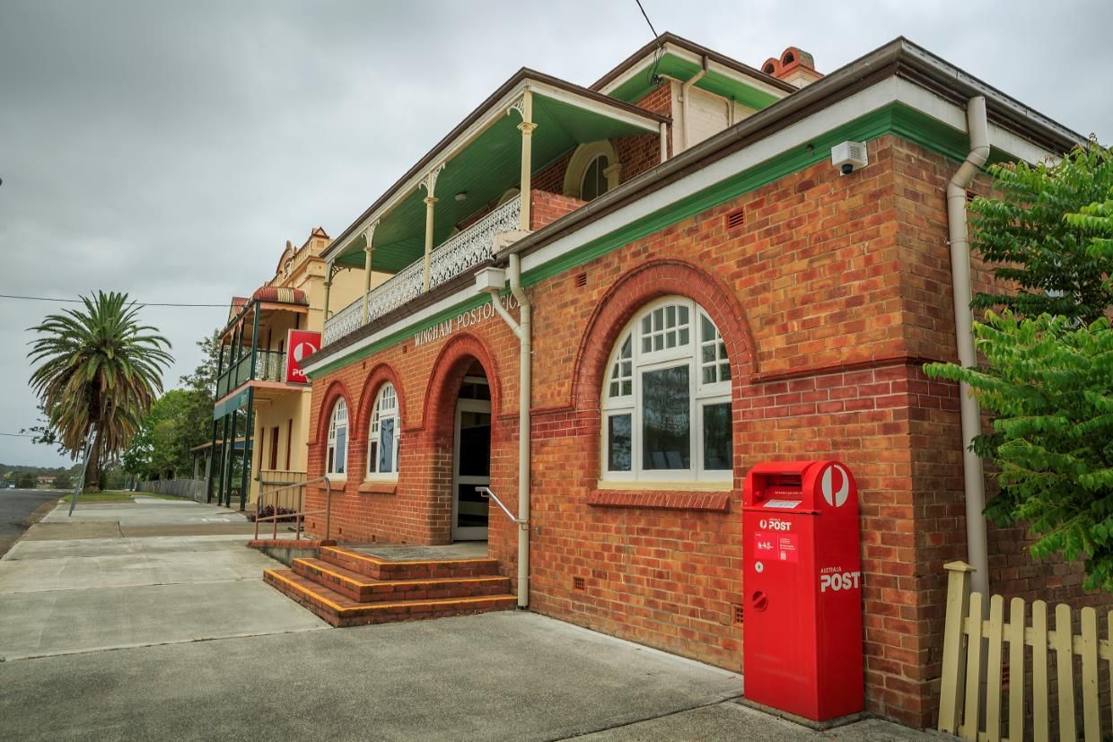 A Brick Building With Arches, a Red Mailbox, and a Balcony — The Cheapy Shop in Wingham, NSW