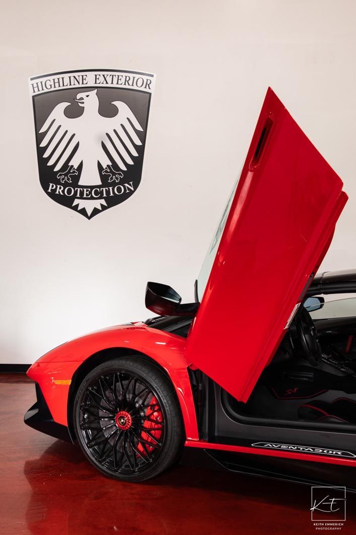 Red Lamborghini with door open, in front of a badge with an eagle.