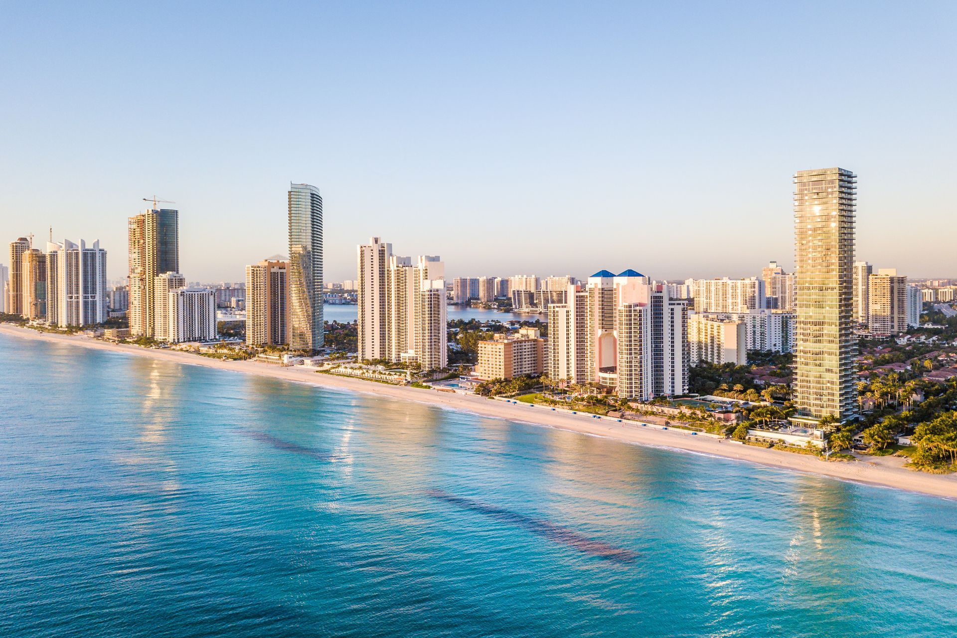 Beachfront cityscape with high-rise buildings and turquoise ocean under a clear sky.