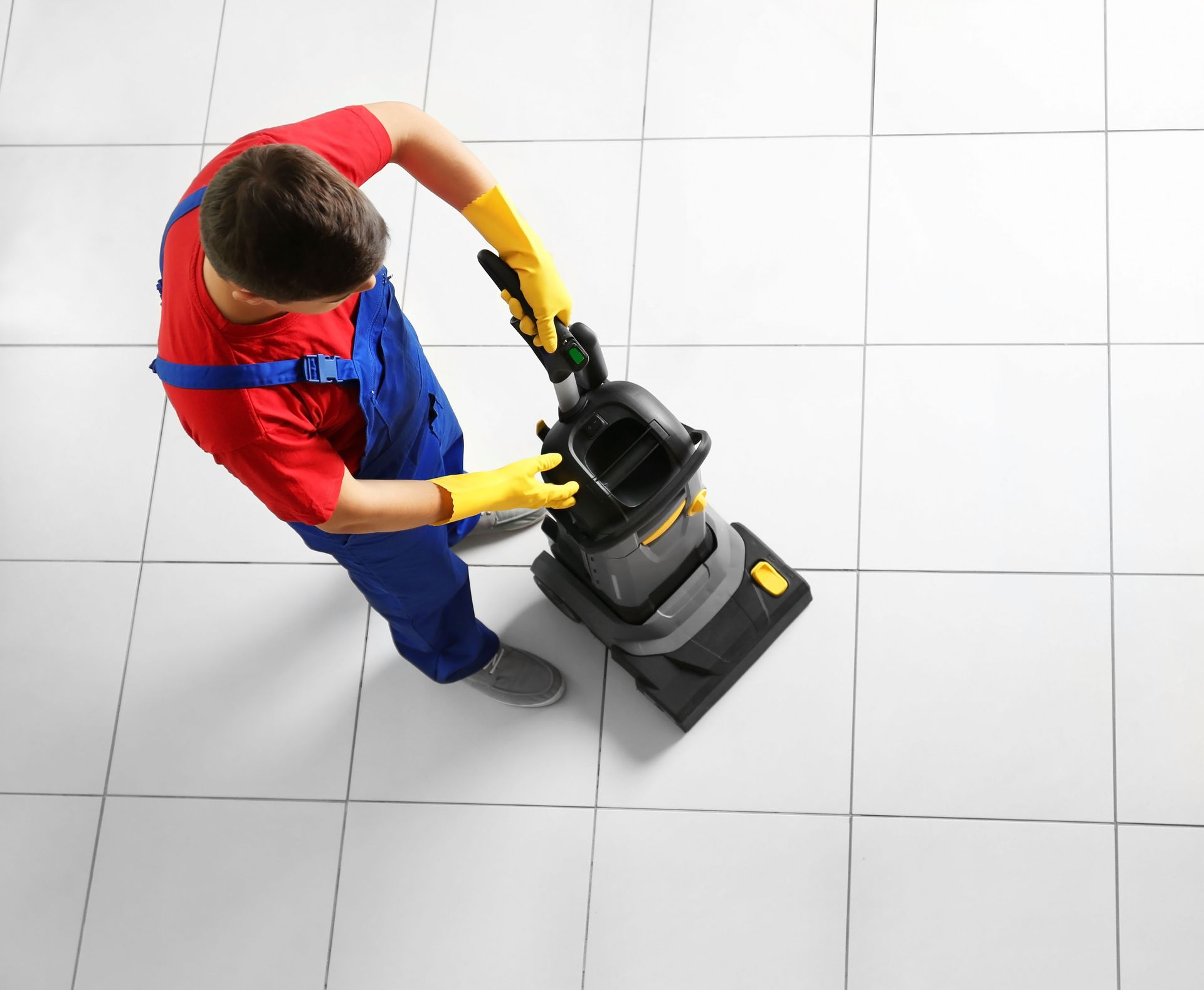a man is using a vacuum cleaner on a tiled floor .