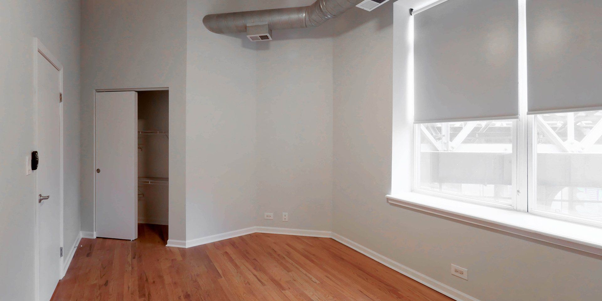 An empty room with hardwood floors and a large window at 1550 North Damen.