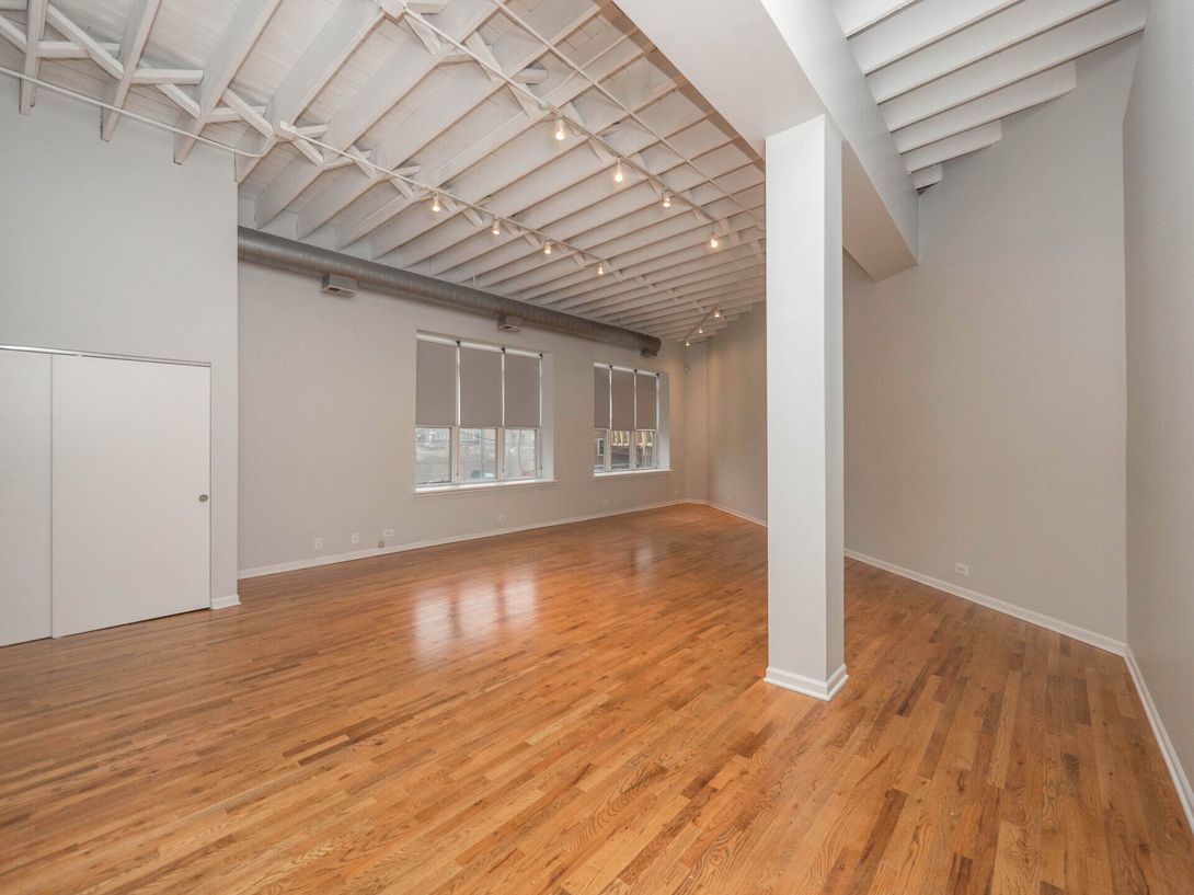 An empty room with hardwood floors and white walls at 1550 North Damen.