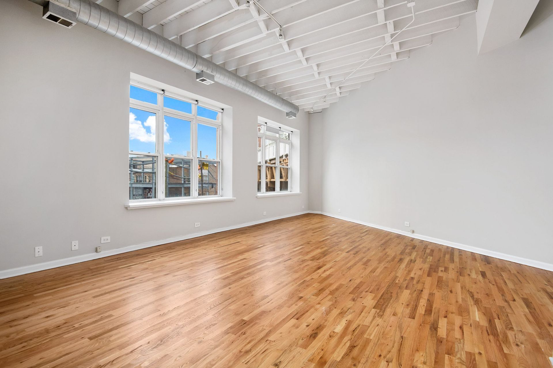 an empty living room with wood floors and a large window