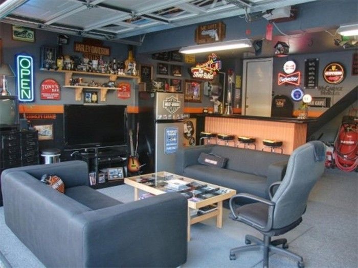 Garage with a bar, sofas, TV, and Harley Davidson decor.