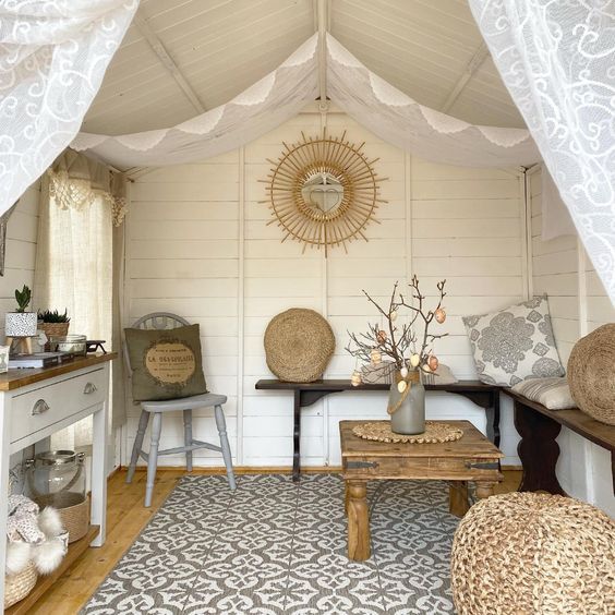 Cozy, light-filled cabin interior with rustic decor: wooden furniture, patterned rug, and floral accents.