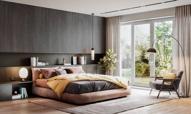 Modern bedroom with bed, window overlooking a garden, gray and gold decor.