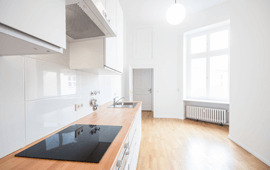 Modern white kitchen with wood countertops and a large window.