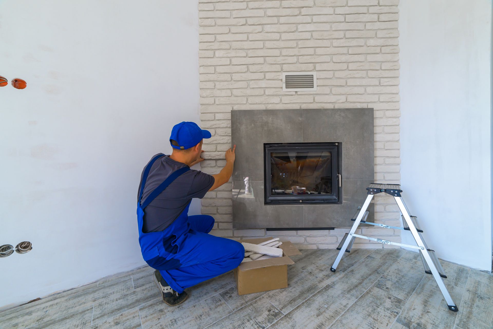 Technician aligning panels on modern fireplace install.