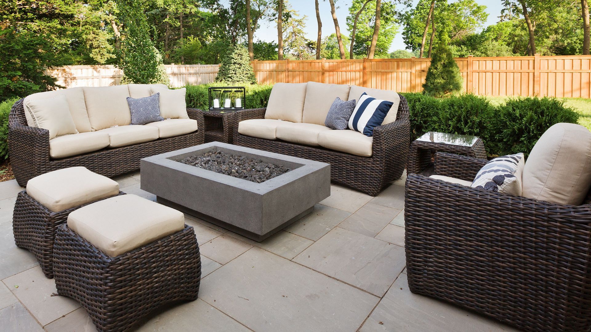 Outdoor seating area with wicker furniture, a fire pit, and stone patio.