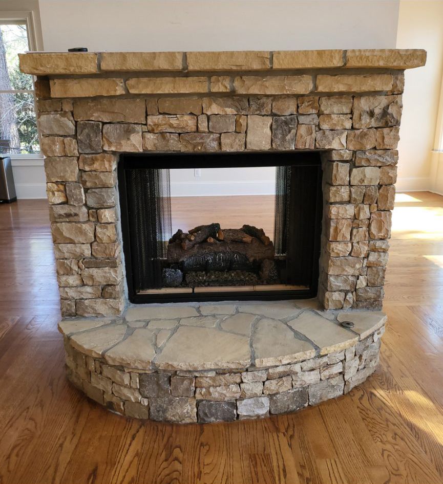 Stone fireplace with dark interior, on wood floor.