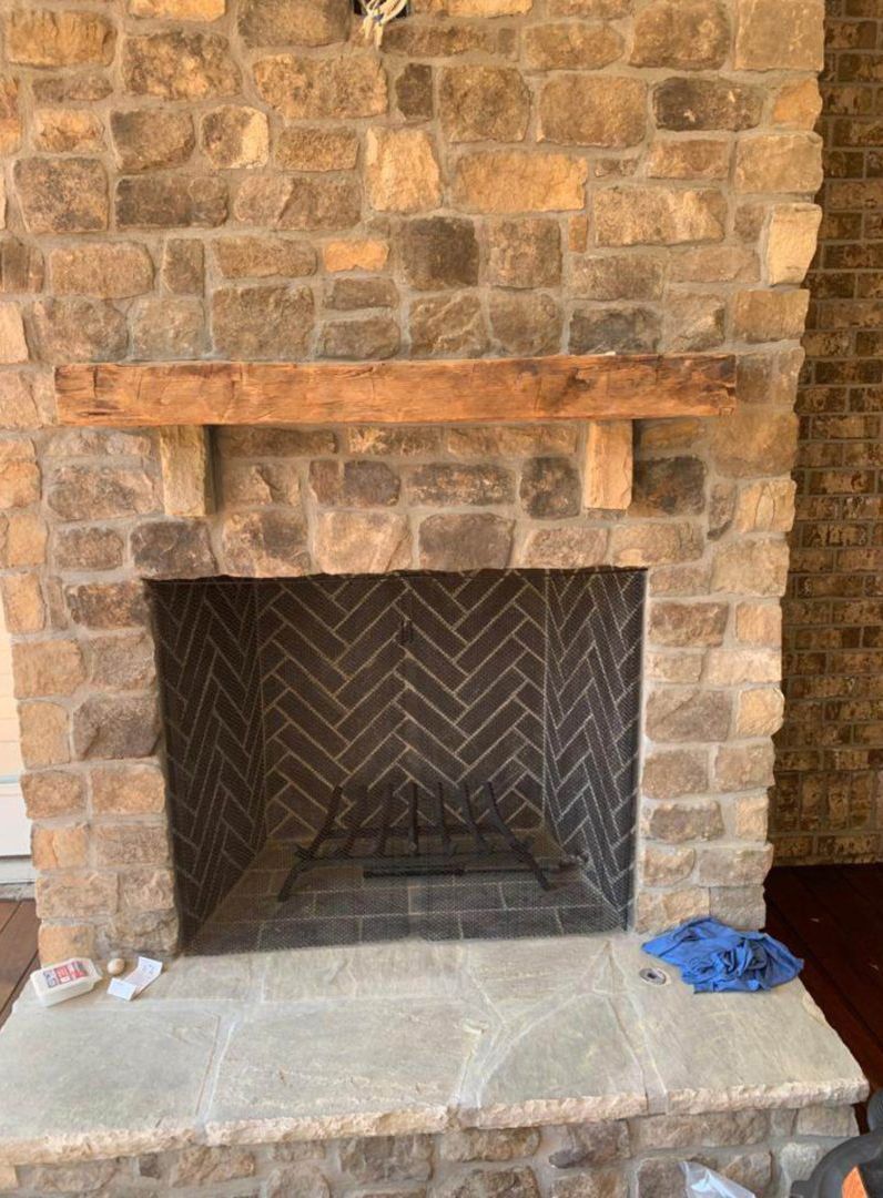 Stone fireplace with herringbone brick interior, wooden mantel.