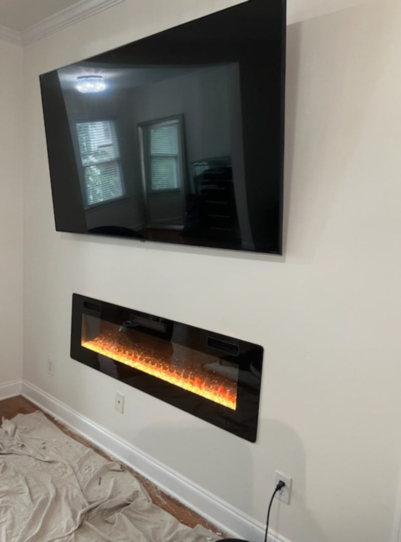 Flat-screen TV mounted above a modern electric fireplace on a white wall.