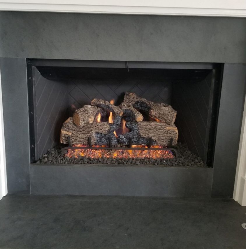 Gas fireplace with burning logs and black surround.