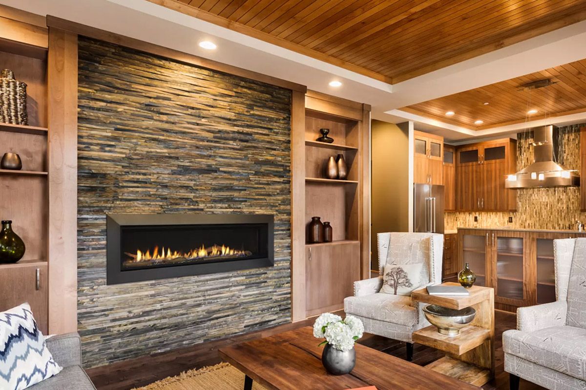 Living room with stone fireplace, wood paneling, and seating.
