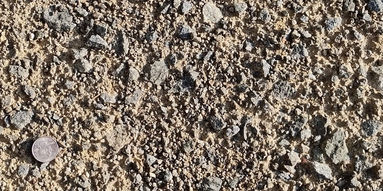 Gravel and sand texture with a coin for scale.