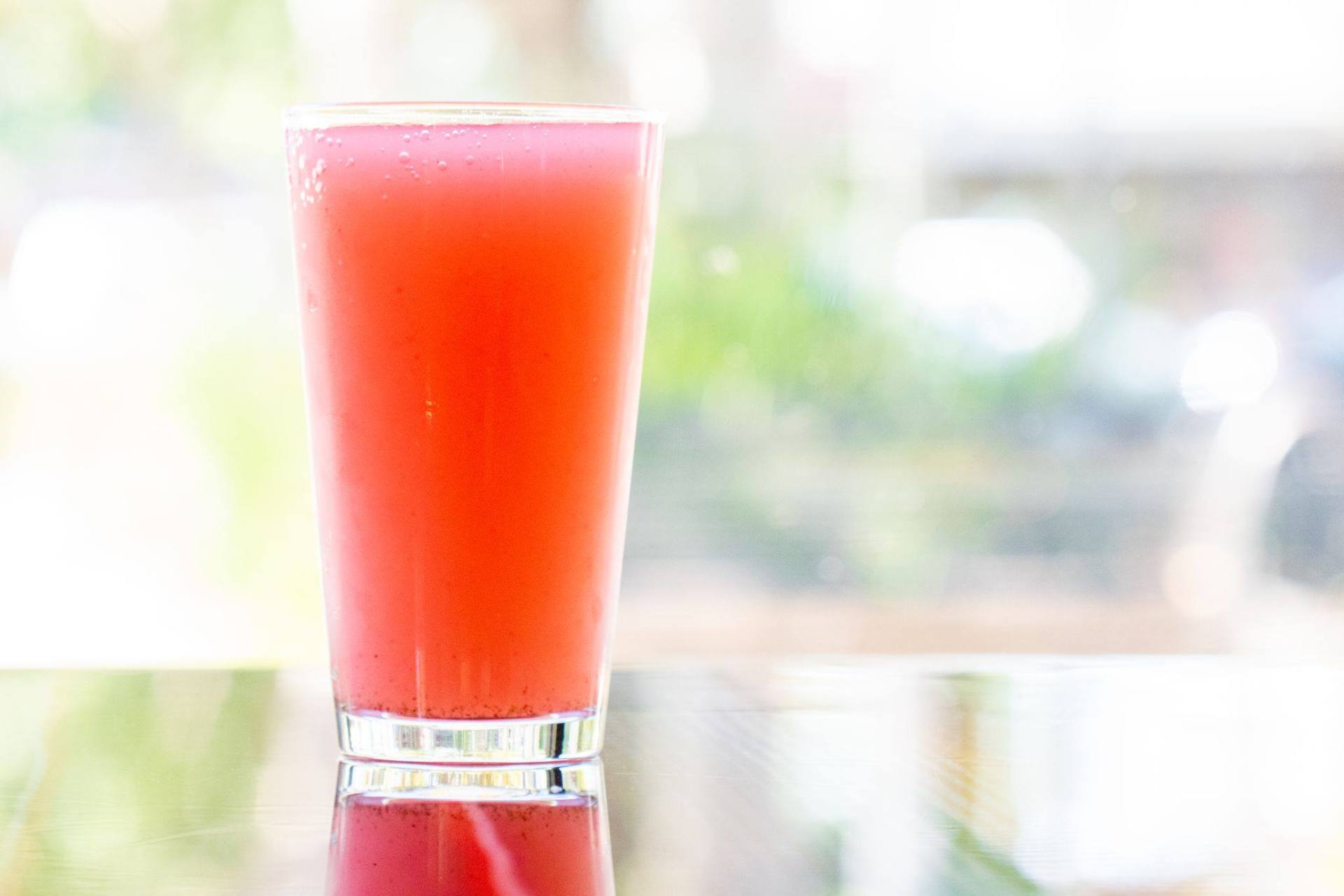A glass of watermelon juice with a straw on a table.