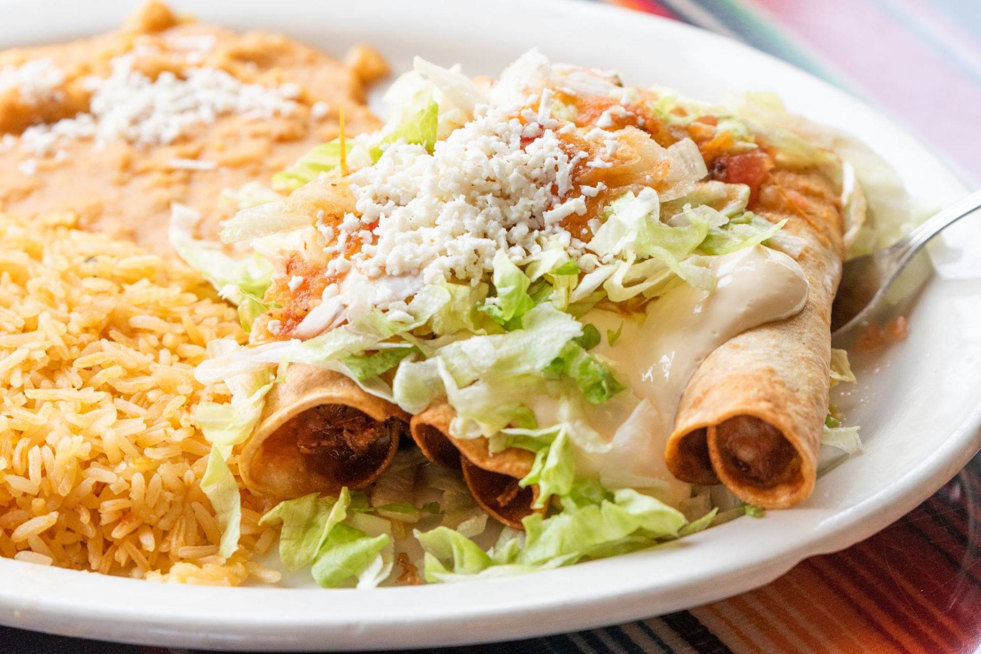 A close up of a plate of food with rice and tacos on a table.