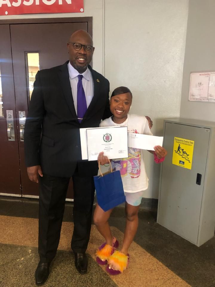 A man in a suit and tie is standing next to a young girl holding a certificate.