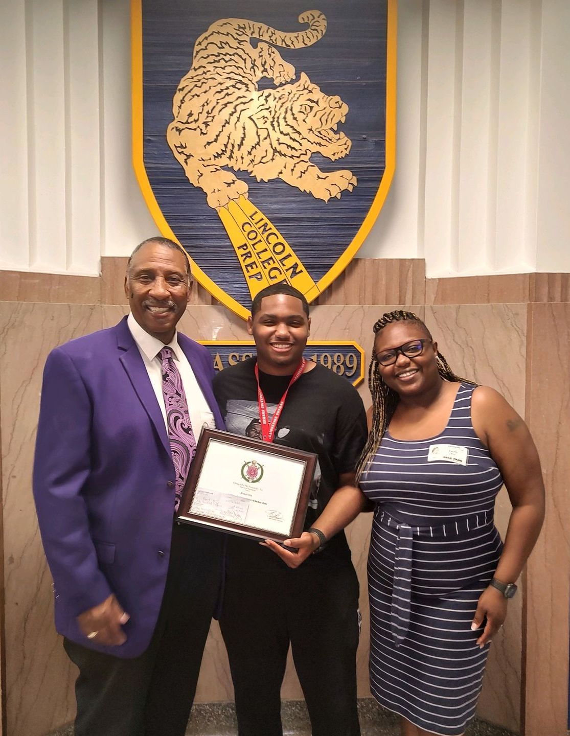 A man in a purple suit is holding a certificate