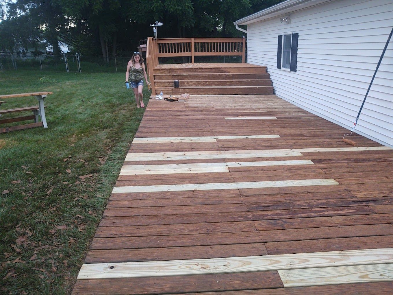A woman is walking down a wooden deck in front of a house.