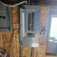 A electrical box is hanging on a wooden wall in a garage.
