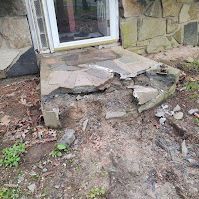A stone walkway is being demolished in front of a house.