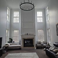 A living room with a fireplace , couch , chairs and a chandelier.