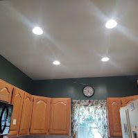 A kitchen with wooden cabinets and a clock on the wall.